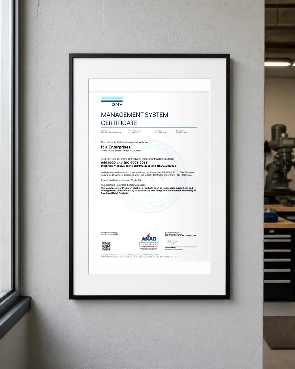 Framed DNV Management System Certificate for AS9100D and ISO 9001:2015 issued to R J Enterprises, hanging on the shop office wall