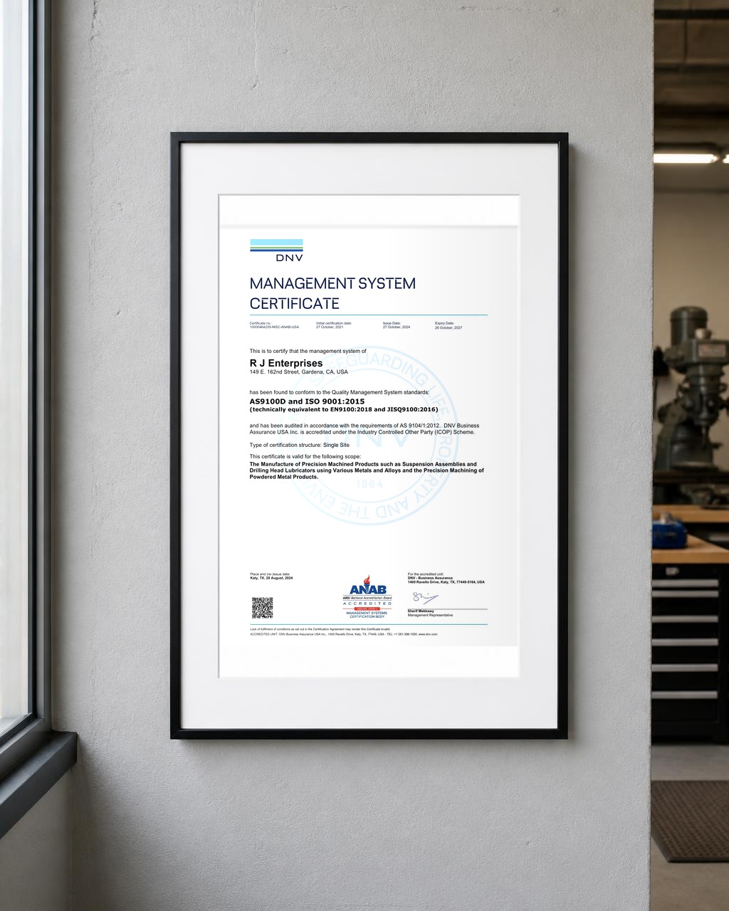 Framed DNV Management System Certificate for AS9100D and ISO 9001:2015 issued to R J Enterprises, hanging on the shop office wall