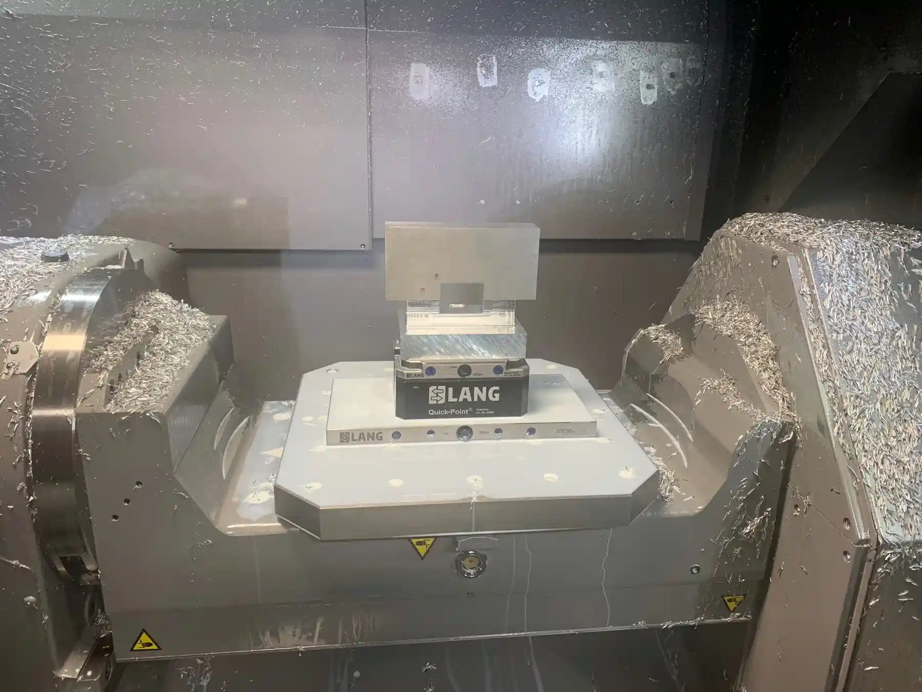 Machining center interior with a part on the trunnion and chips on the way covers
