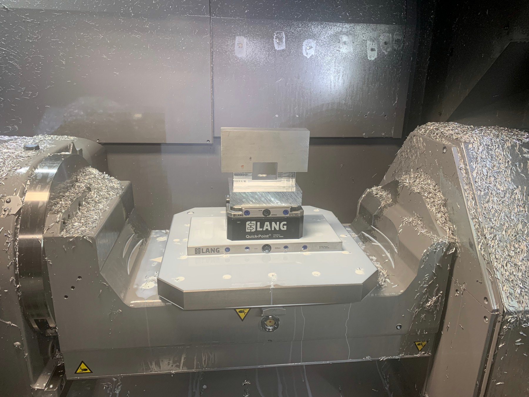 Machining center interior with a part on the trunnion and chips on the way covers