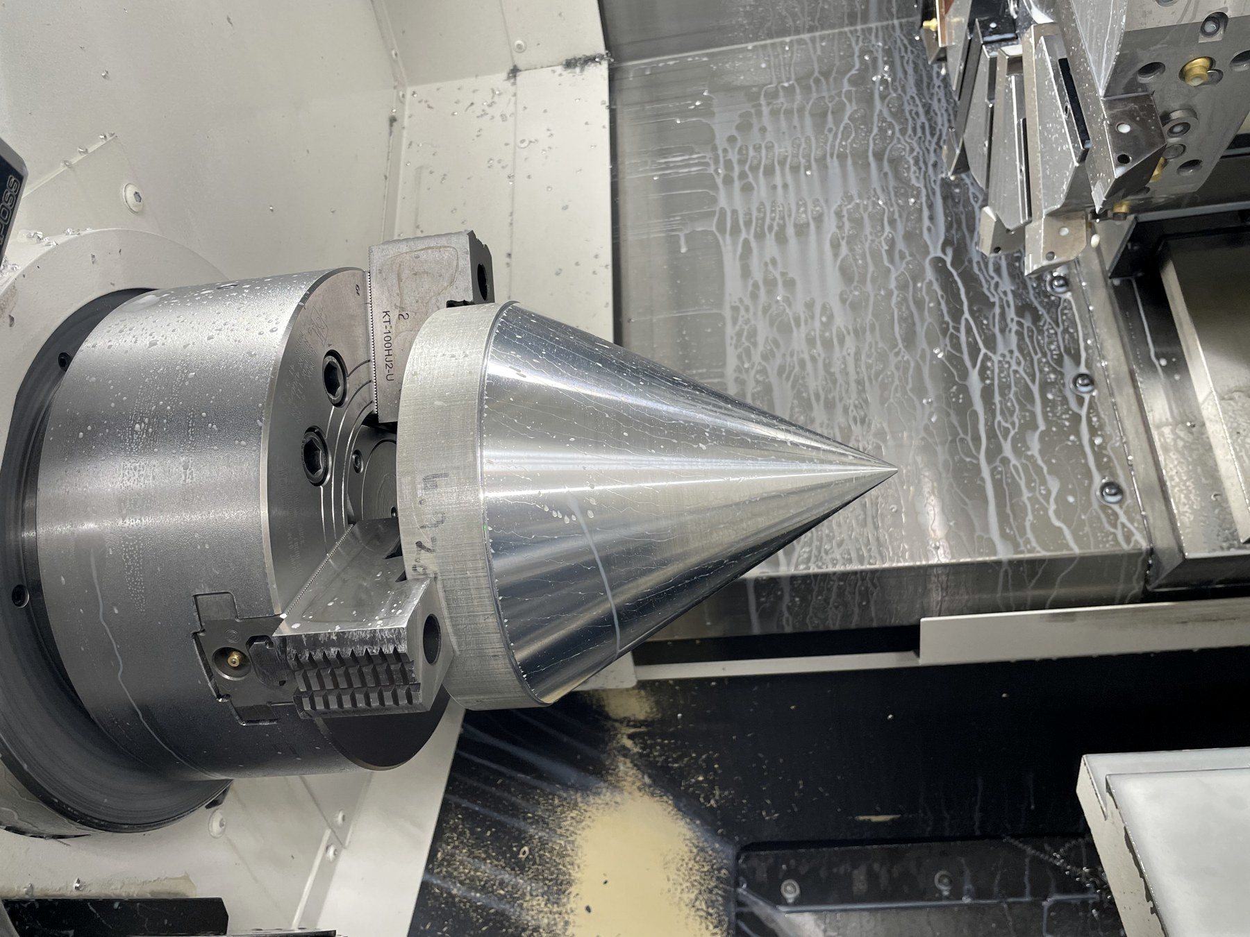 Turning center chuck gripping a machined steel component