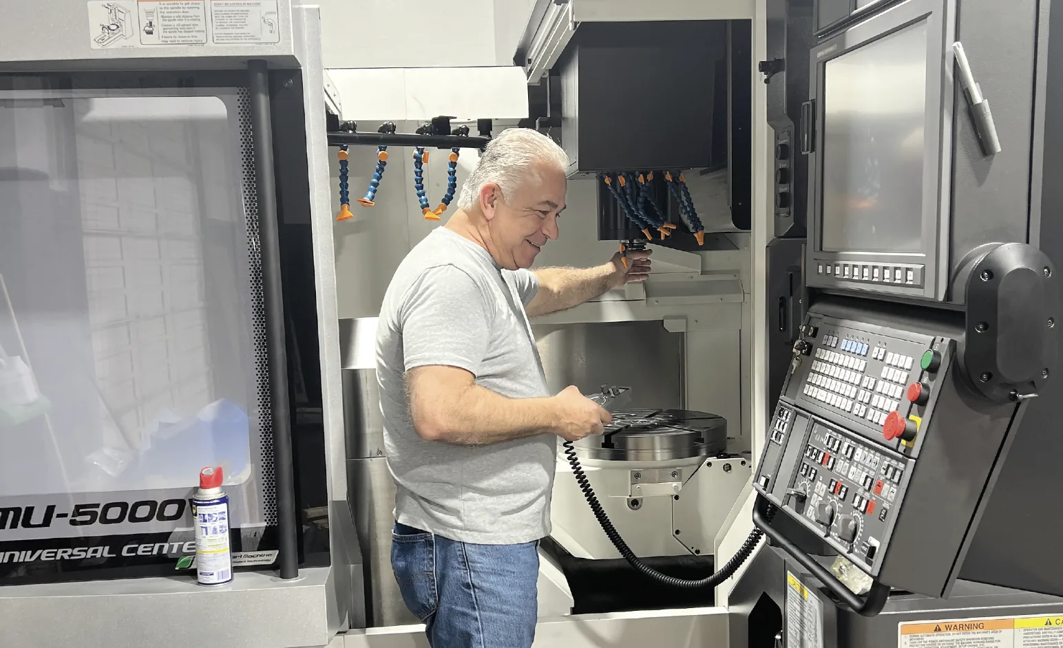 Vartan Akrabian loading tooling into an Okuma MU-5000V universal machining center at RJ Enterprises